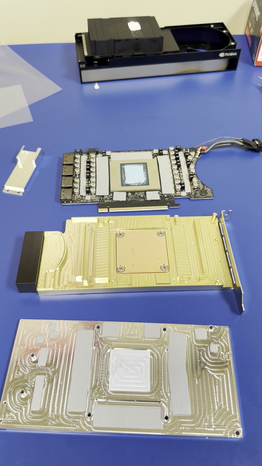 The card stripped down with thermal paste on the die, the Optimus block and backplate laid out — all ready to go (a frame from the build video)